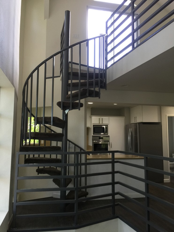 Imagen de escalera de caracol actual de tamaño medio con escalones de acrílico y barandilla de metal