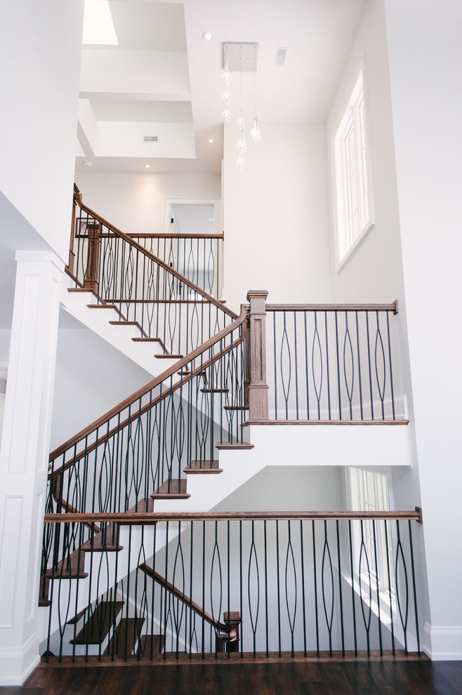This is an example of an expansive contemporary wood u-shaped mixed railing staircase in Toronto with wood risers.