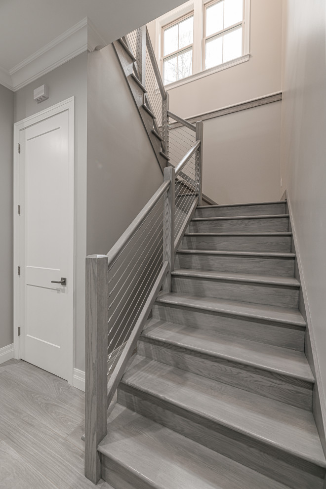 アトランタにある高級な広いトランジショナルスタイルのおしゃれな折り返し階段 (木の蹴込み板、ワイヤーの手すり) の写真