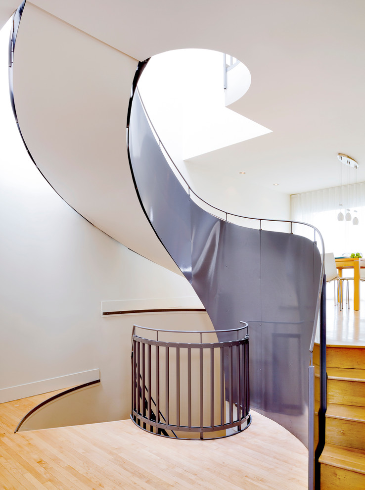 На фото: изогнутая деревянная лестница в современном стиле с деревянными ступенями с