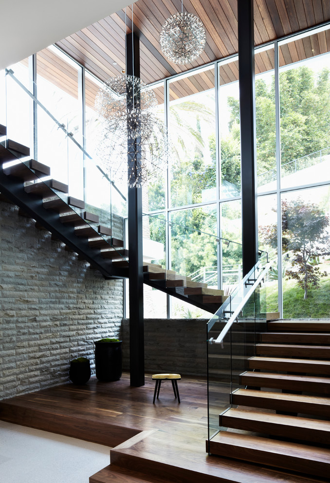 Réalisation d'un grand escalier courbe minimaliste avec des marches en bois, des contremarches en bois et éclairage.