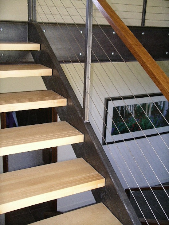 Стильный дизайн: большая угловая металлическая лестница в стиле модернизм с деревянными ступенями и перилами из тросов - последний тренд
