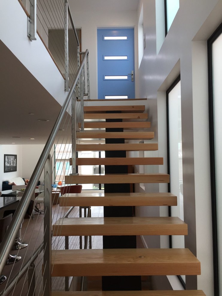 На фото: большая деревянная лестница на больцах в стиле модернизм с деревянными ступенями и металлическими перилами