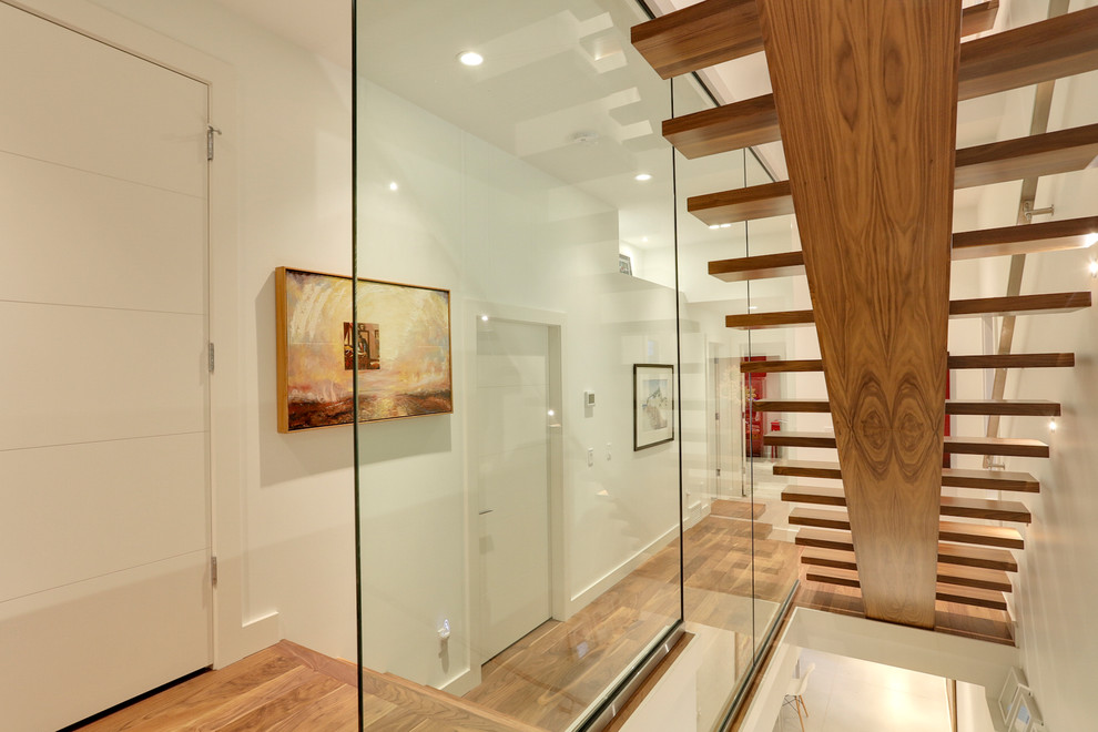 This is an example of a contemporary wood straight staircase in Calgary with wood risers.