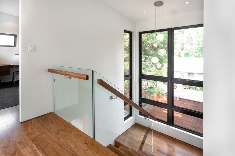 Inspiration for a large midcentury wood u-shaped glass railing staircase in Vancouver with wood risers.