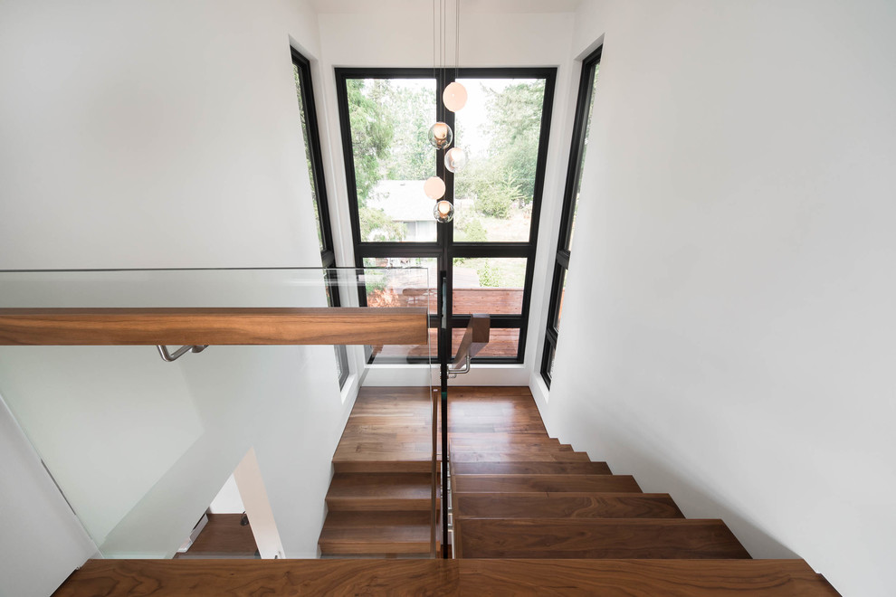 На фото: большая п-образная деревянная лестница в стиле ретро с деревянными ступенями и стеклянными перилами с