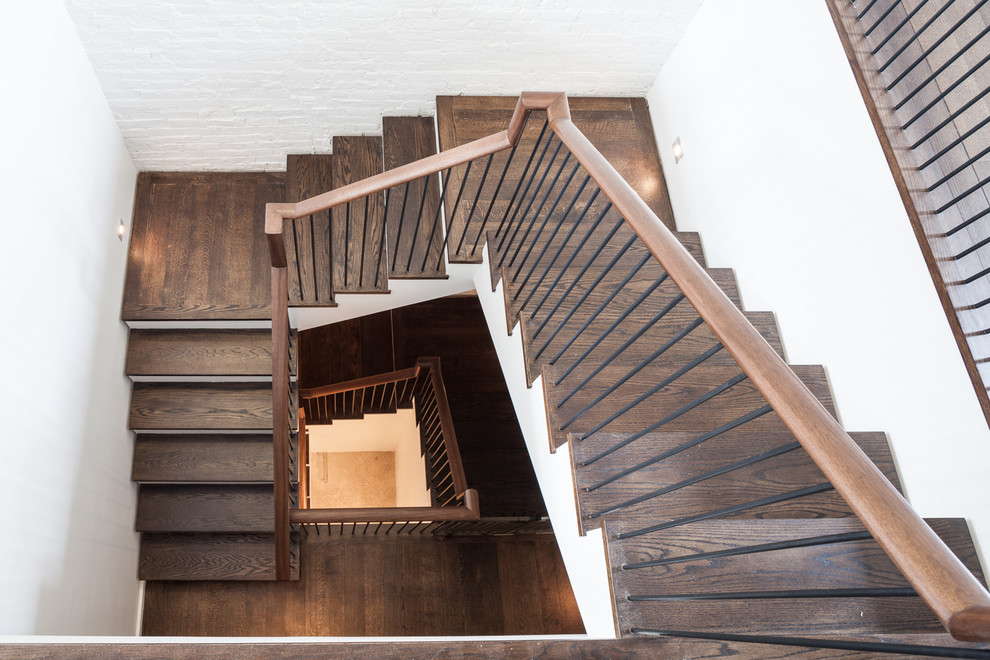 Imagen de escalera en U tradicional grande con escalones de madera, barandilla de madera y contrahuellas de madera pintada