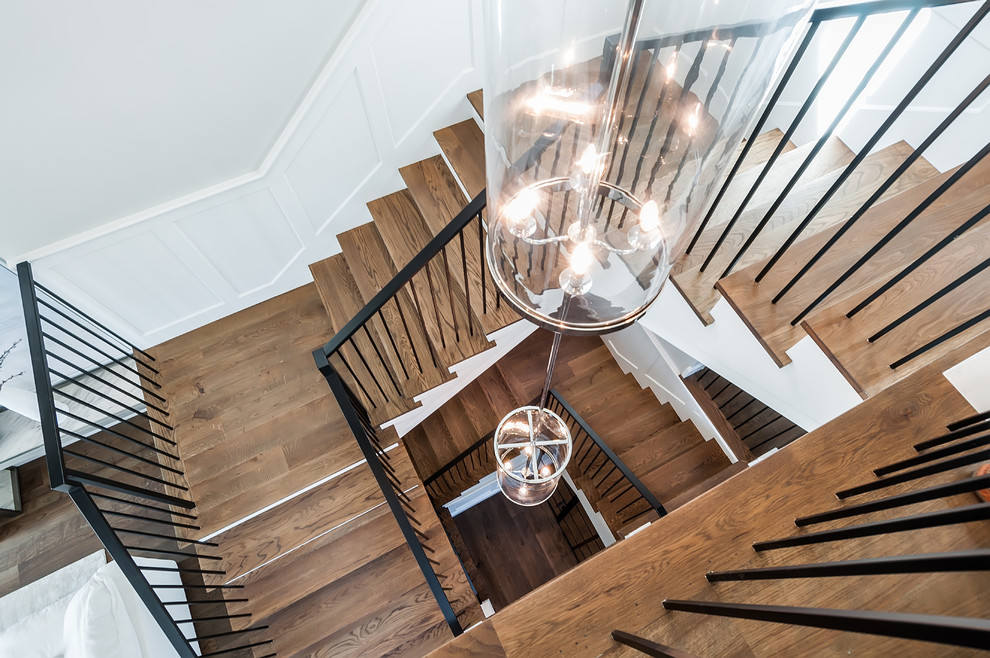 This is an example of a large traditional wood u-shaped metal railing staircase in Los Angeles with painted wood risers.
