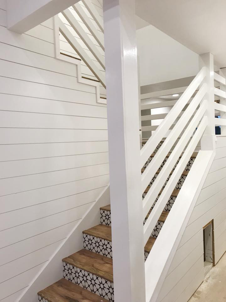 На фото: изогнутая деревянная лестница среднего размера в стиле кантри с крашенными деревянными ступенями и деревянными перилами с
