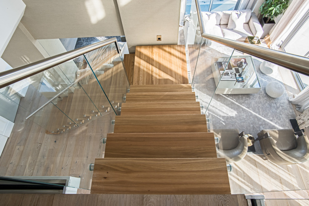 Imagen de escalera en L minimalista grande sin contrahuella con escalones de madera y barandilla de vidrio