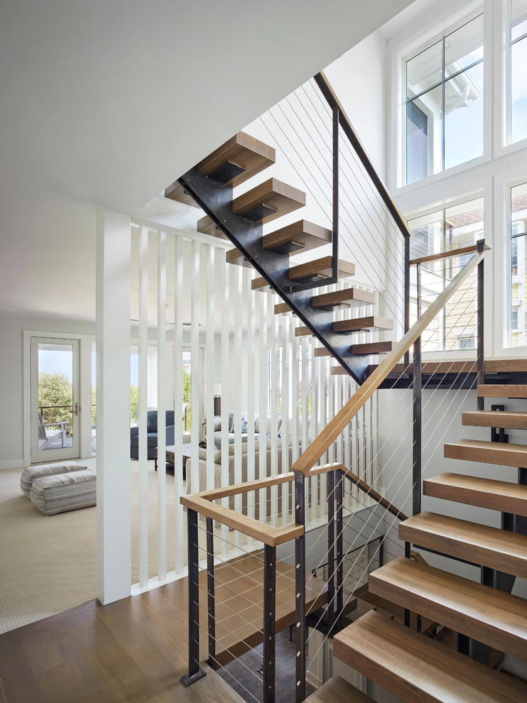 На фото: большая п-образная металлическая лестница в морском стиле с деревянными ступенями и перилами из смешанных материалов с