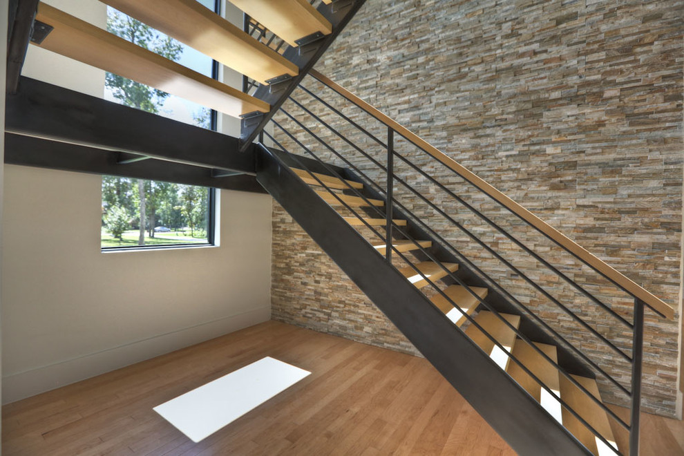 Réalisation d'un grand escalier design en L avec des marches en bois et des contremarches en métal.