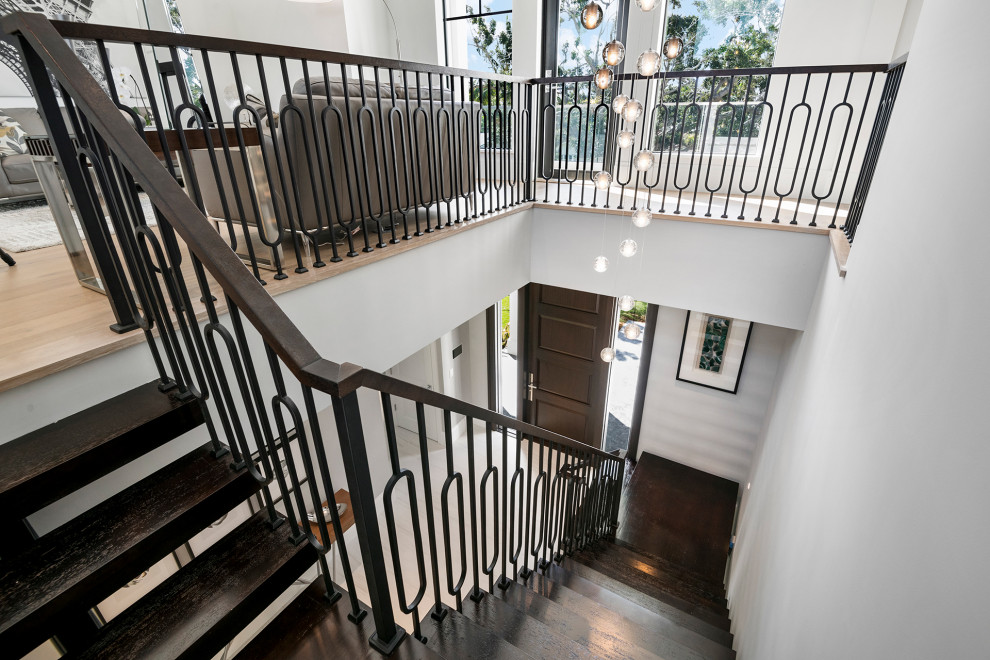 This is an example of a large classic wood floating wood railing staircase in Miami.