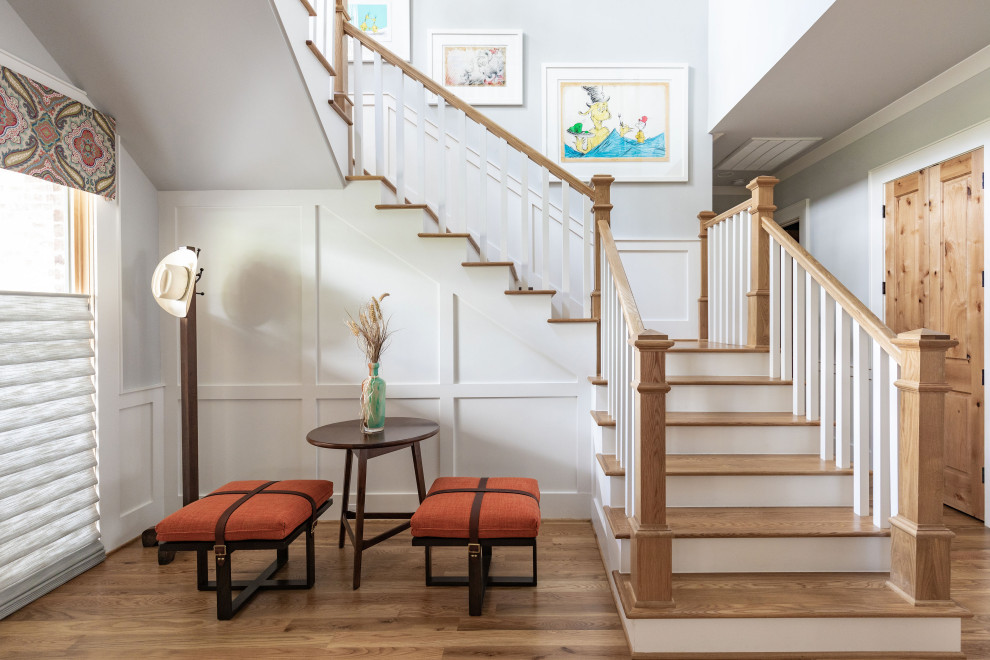 Modelo de escalera en U de estilo de casa de campo grande con escalones de madera, contrahuellas de madera pintada y barandilla de madera