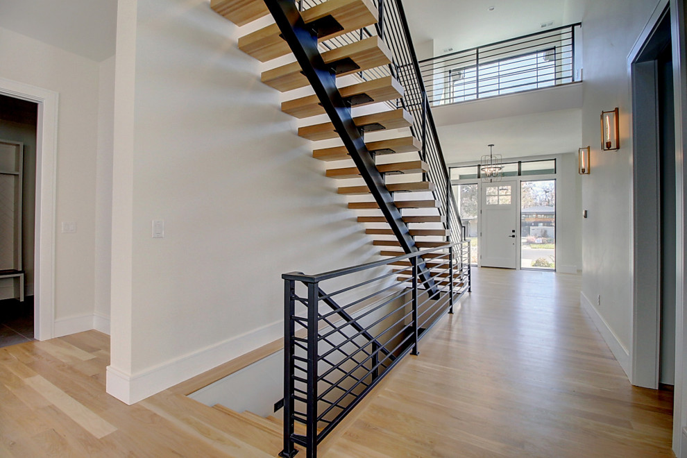 Photo of a large traditional wood floating metal railing staircase in Denver with open risers.