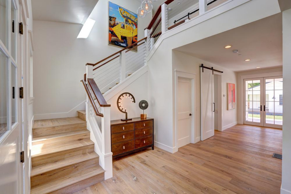 Imagen de escalera en U de estilo de casa de campo grande con escalones de madera, contrahuellas de madera y barandilla de cable