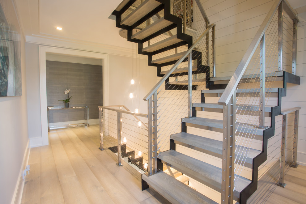 Ejemplo de escalera suspendida minimalista grande con escalones de madera, contrahuellas de metal y barandilla de metal