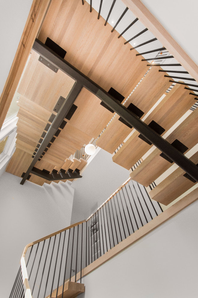 Imagen de escalera en U moderna grande sin contrahuella con escalones de madera y barandilla de metal