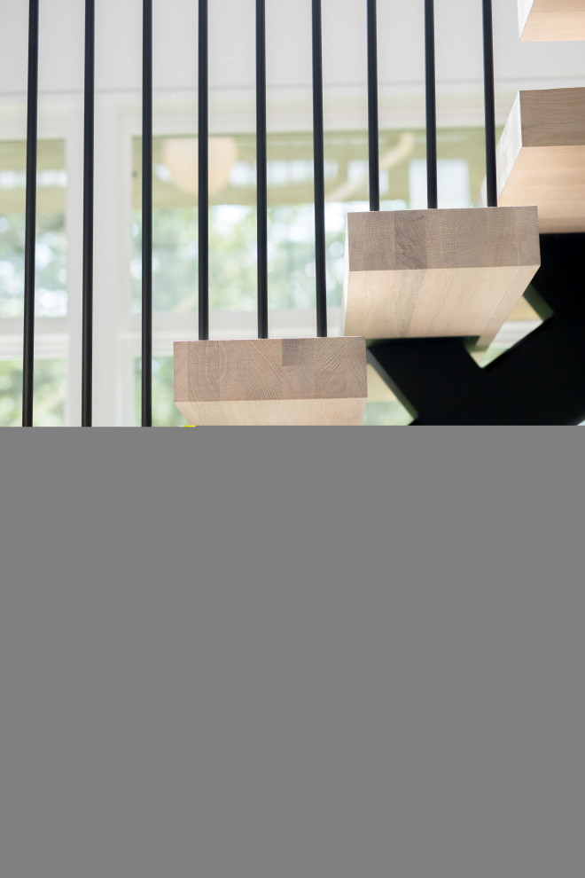 Imagen de escalera en U moderna grande sin contrahuella con escalones de madera y barandilla de metal