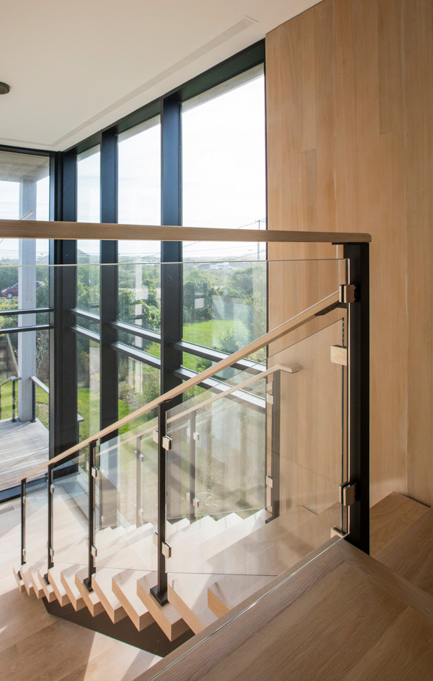 На фото: угловая деревянная лестница среднего размера в стиле модернизм с деревянными ступенями и перилами из тросов с
