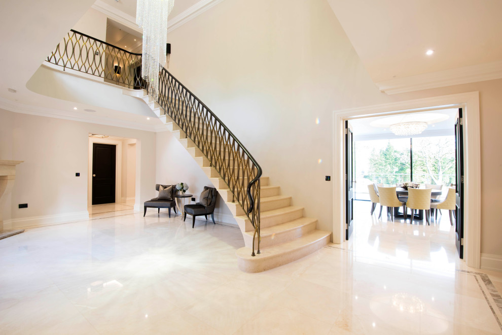 Example of a large minimalist travertine curved metal railing staircase design in West Midlands with travertine risers