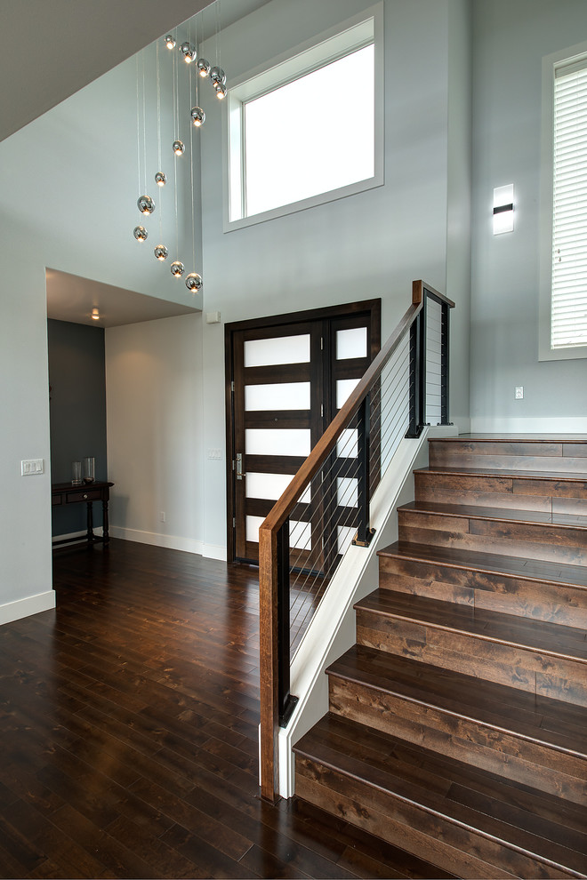 Cette image montre un escalier minimaliste en L de taille moyenne avec des marches en bois, des contremarches en bois et un garde-corps en câble.