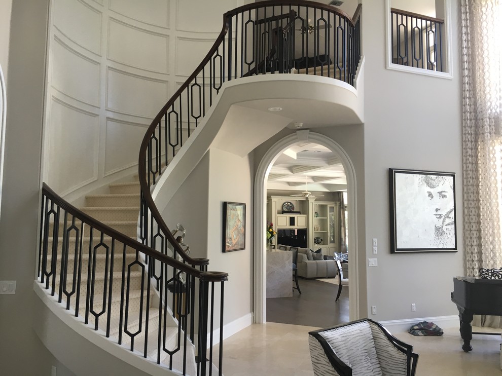 Cette image montre un grand escalier courbe minimaliste avec des marches en moquette, des contremarches en moquette et un garde-corps en bois.