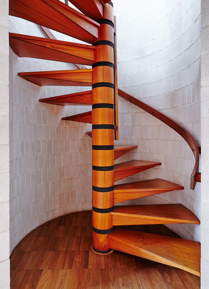 This is an example of a large contemporary wood spiral staircase in Cambridgeshire with open risers.