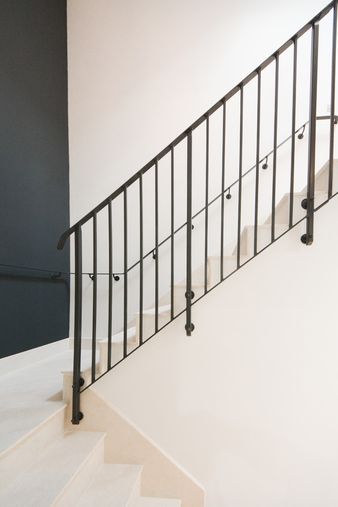 Diseño de escalera en U minimalista grande con escalones de piedra caliza, contrahuellas de piedra caliza y barandilla de metal