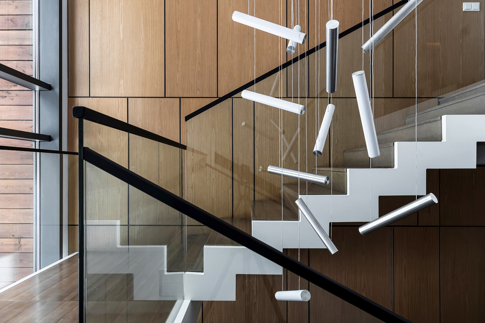 Inspiration pour un escalier minimaliste en L de taille moyenne avec des marches en travertin, des contremarches en bois et un garde-corps en verre.
