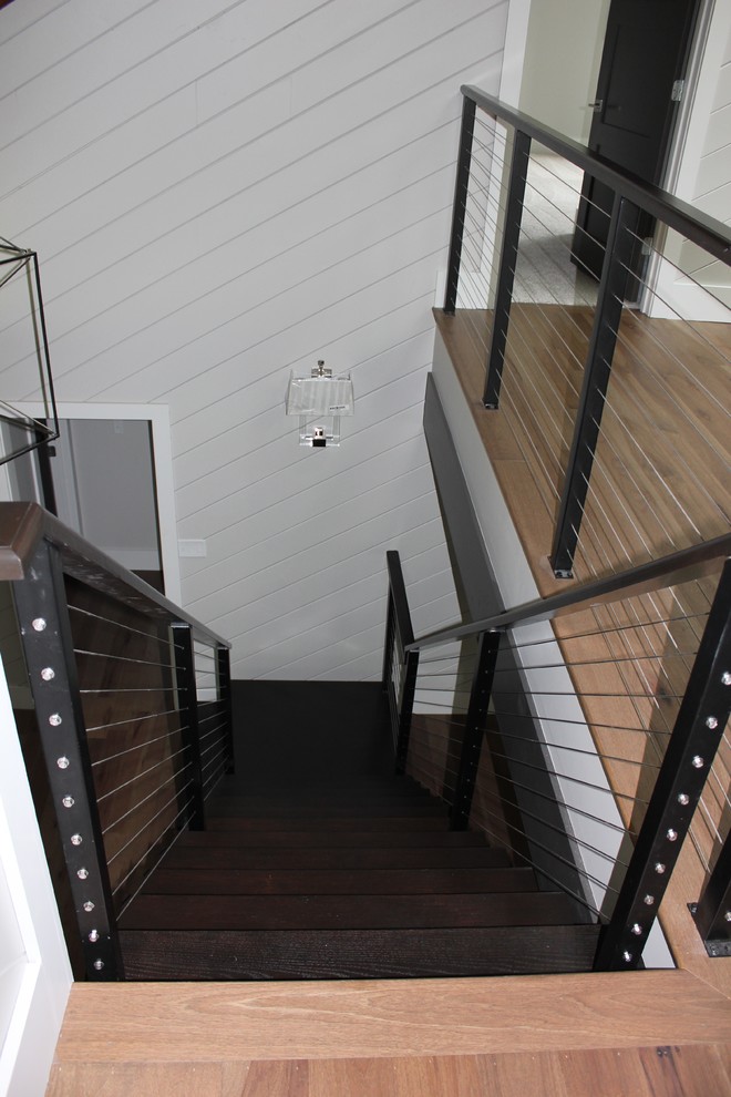На фото: огромная прямая лестница в стиле неоклассика (современная классика) с деревянными ступенями и перилами из тросов с