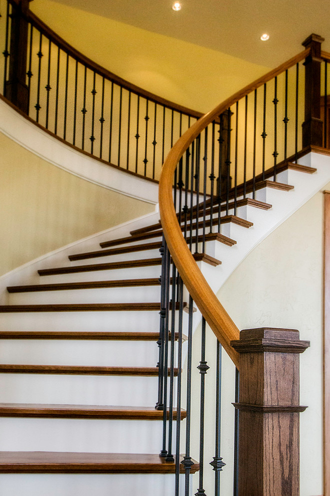Cette photo montre un escalier courbe chic de taille moyenne avec des marches en bois, des contremarches en bois et un garde-corps en métal.