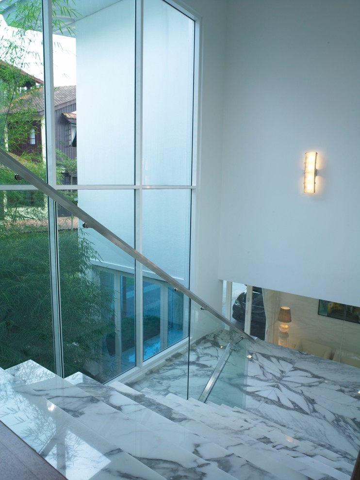 Идея дизайна: большая п-образная лестница в стиле модернизм с мраморными ступенями, подступенками из мрамора и стеклянными перилами