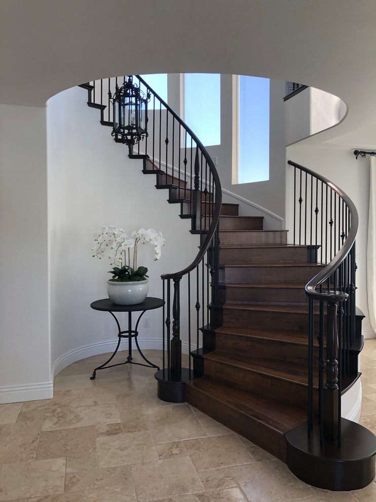 Large mediterranean wood curved mixed railing staircase in Las Vegas with wood risers.