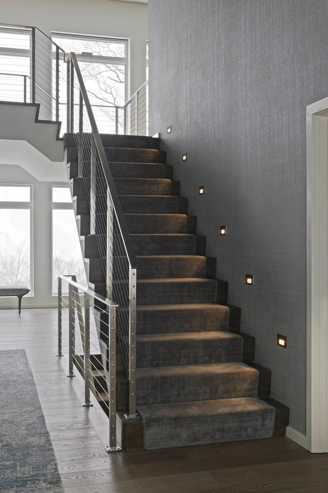 Cette image montre un escalier design en U de taille moyenne avec un garde-corps en métal, des marches en bois et des contremarches en bois.
