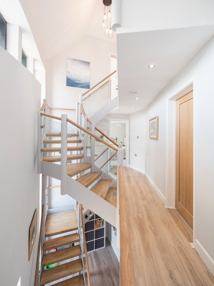 Идея дизайна: изогнутая деревянная лестница среднего размера в стиле модернизм с деревянными ступенями и деревянными перилами