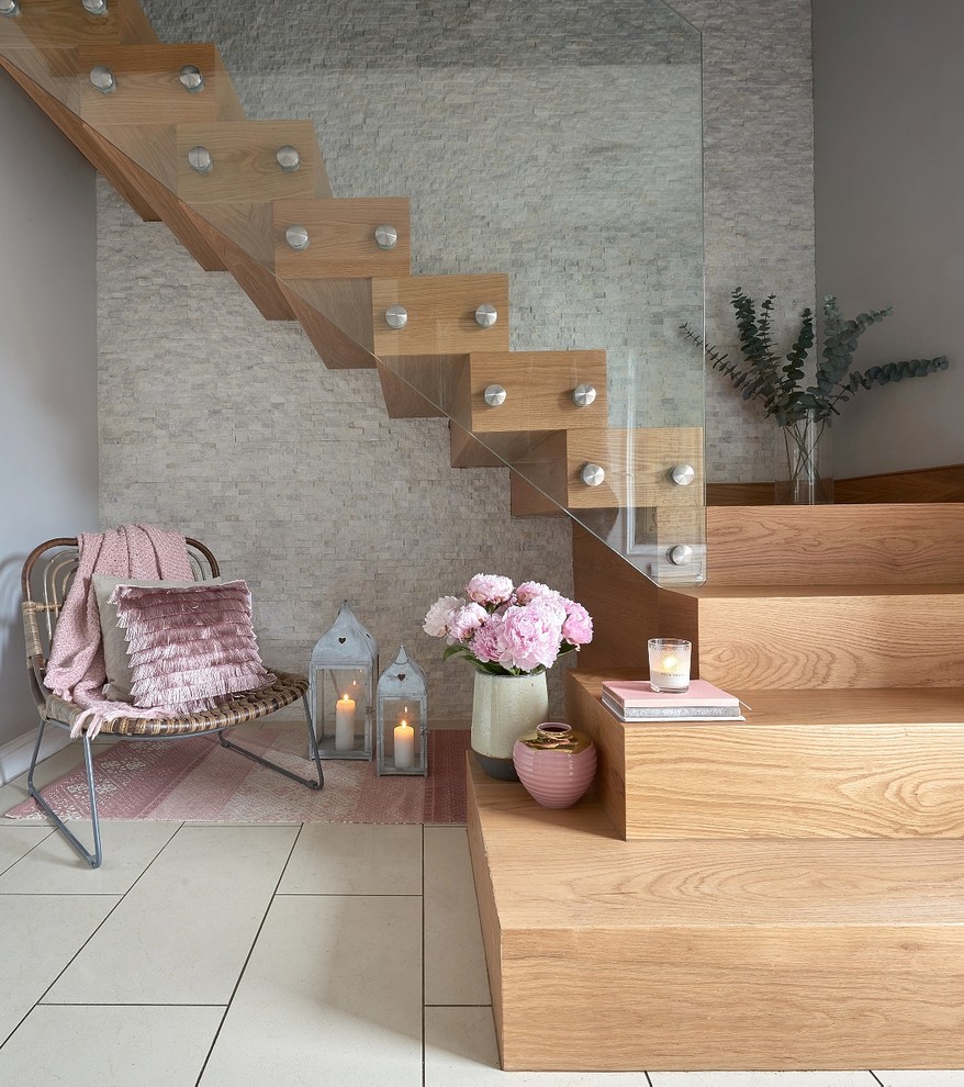 Стильный дизайн: большая деревянная лестница на больцах в современном стиле с деревянными ступенями и стеклянными перилами - последний тренд