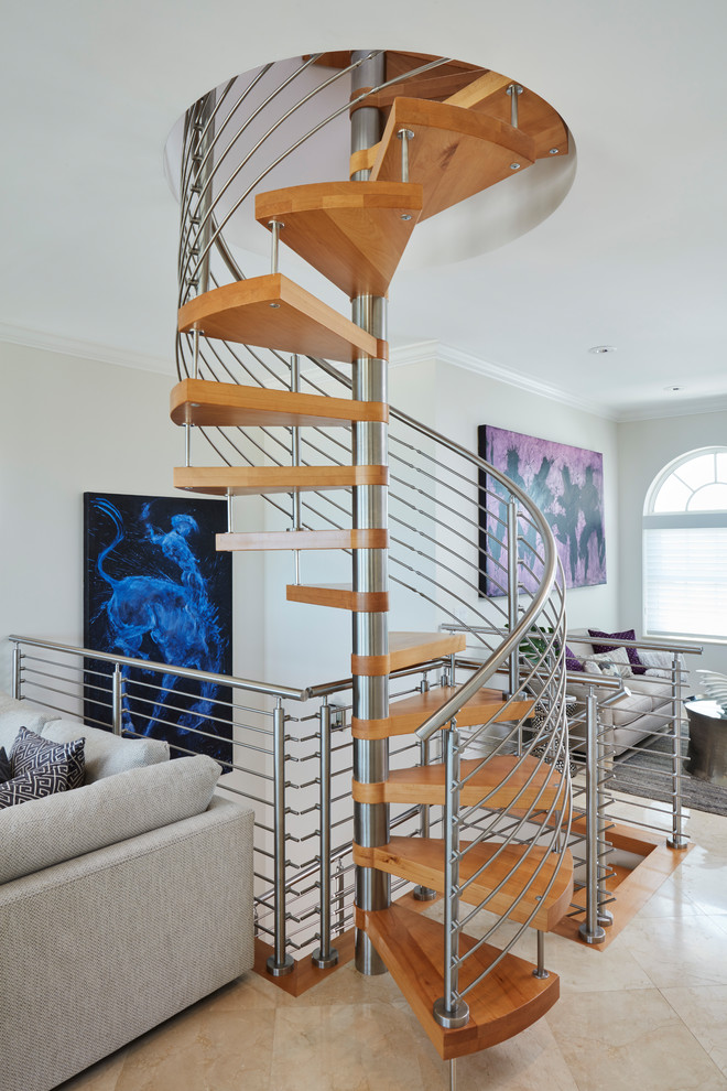 Idée de décoration pour un grand escalier sans contremarche hélicoïdal design avec des marches en bois et un garde-corps en métal.