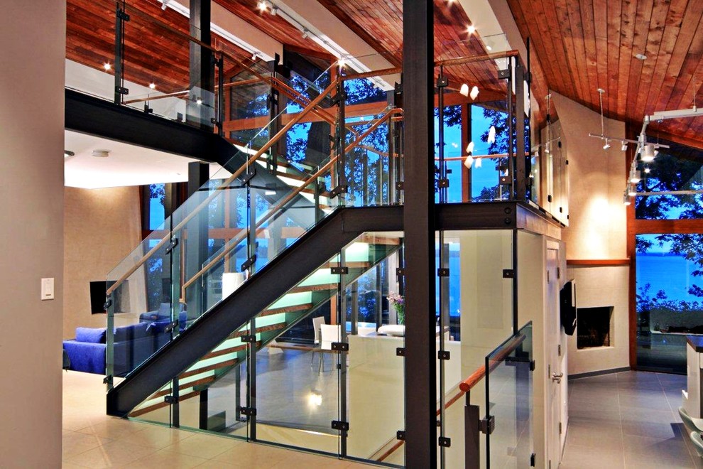 На фото: большая п-образная лестница в стиле модернизм с деревянными ступенями и стеклянными перилами без подступенок с