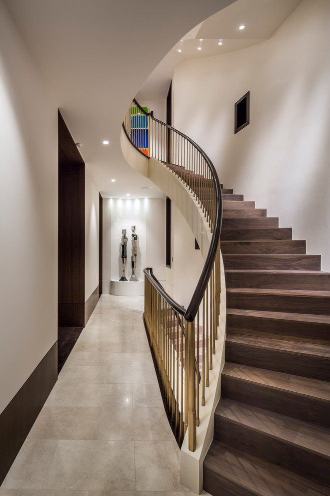 Cette image montre un escalier courbe design avec des marches en bois, des contremarches en bois et un garde-corps en métal.