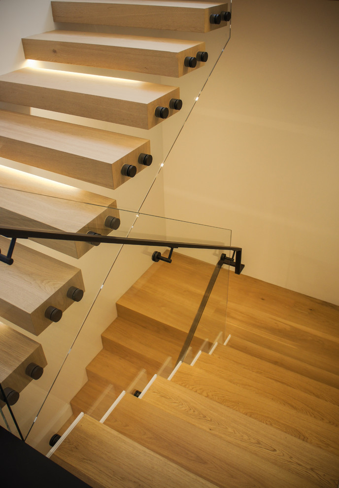 Modelo de escalera en U contemporánea de tamaño medio con escalones de madera, contrahuellas de madera y barandilla de vidrio
