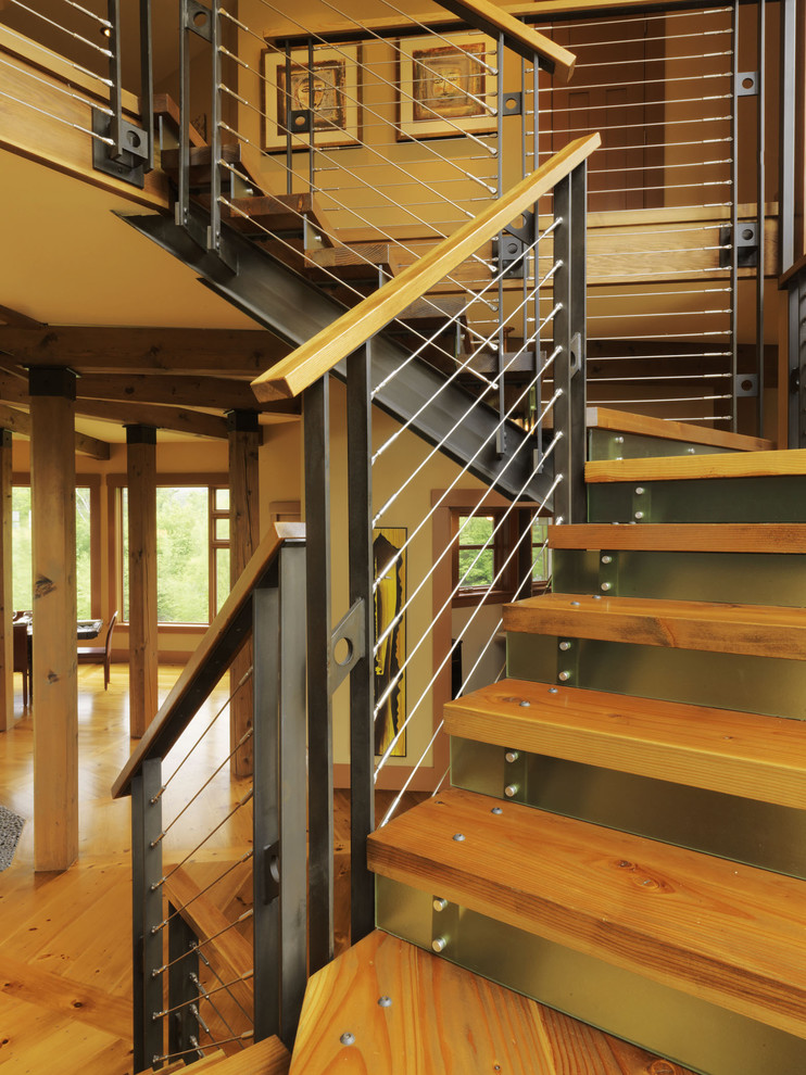 Cette image montre un escalier design avec des contremarches en métal, des marches en bois et un garde-corps en câble.