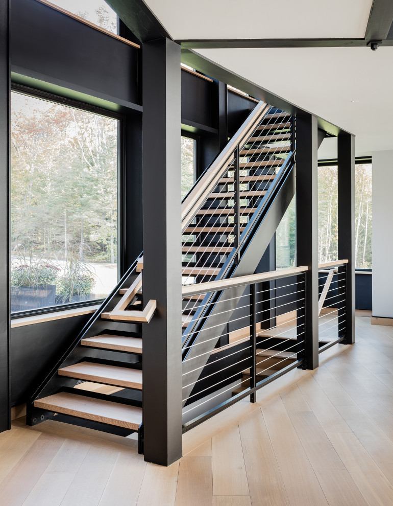 На фото: лестница на больцах в современном стиле с металлическими ступенями и перилами из тросов с