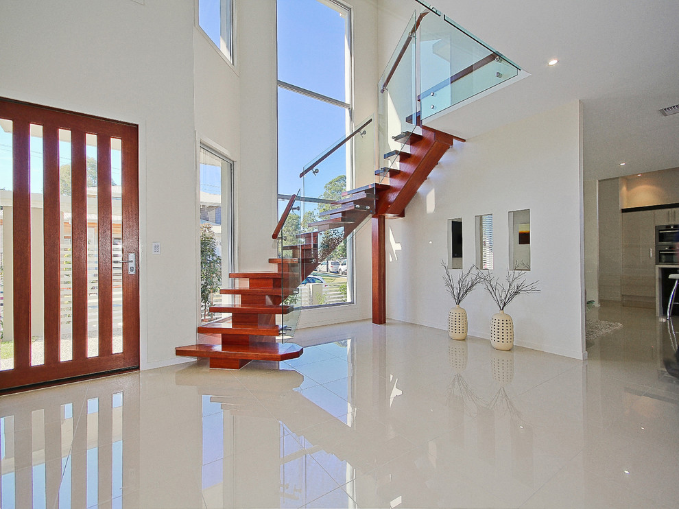 Стильный дизайн: большая изогнутая деревянная лестница в стиле модернизм с деревянными ступенями - последний тренд