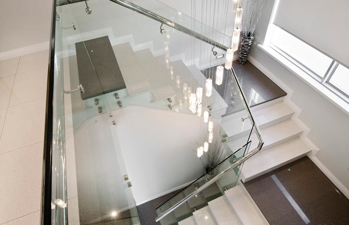 Bild på en stor funkis u-trappa, med klinker, sättsteg i kakel och räcke i glas