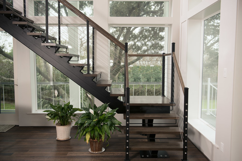 Large beach style wooden floating open and cable railing staircase photo in Houston