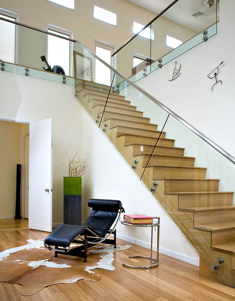 Photo of a contemporary glass railing staircase in Los Angeles with feature lighting.