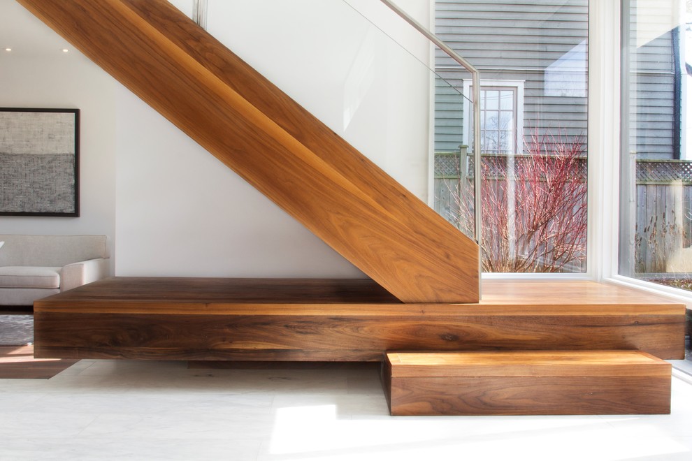 На фото: угловая лестница в стиле модернизм с деревянными ступенями и стеклянными перилами без подступенок с