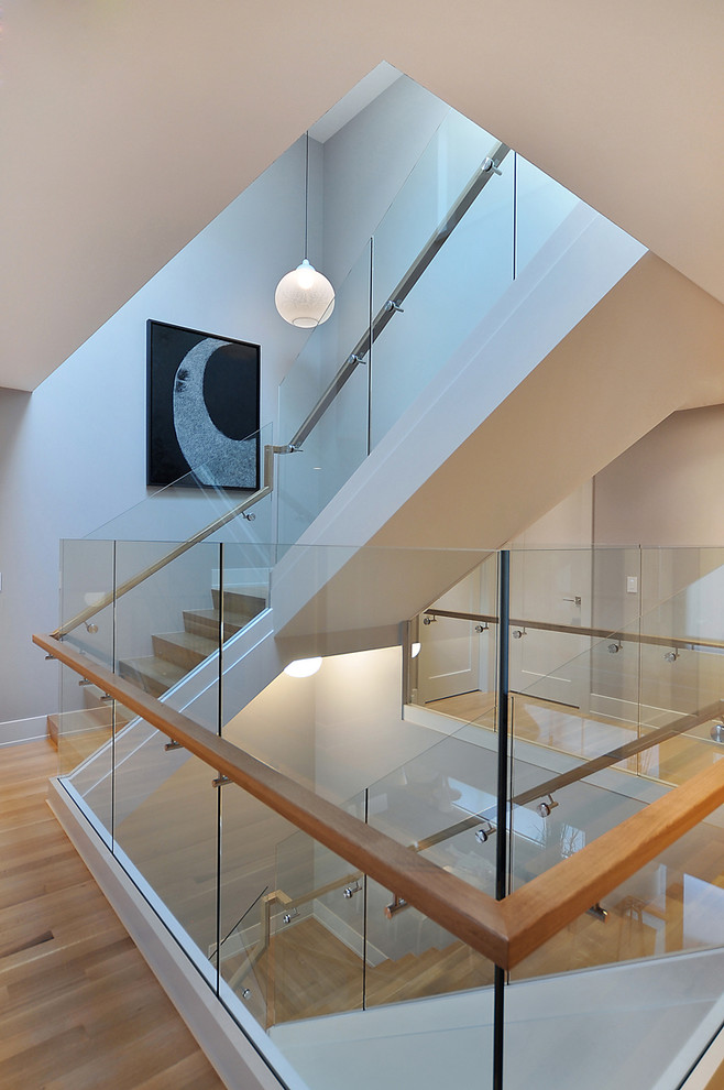 Réalisation d'un escalier minimaliste avec des marches en bois, des contremarches en bois, un garde-corps en verre et palier.