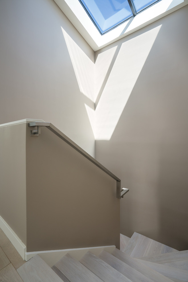Modelo de escalera curva minimalista grande con escalones con baldosas, contrahuellas con baldosas y/o azulejos y barandilla de metal